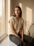Woman wearing a textured asymmetric buttoned knit vest, front
