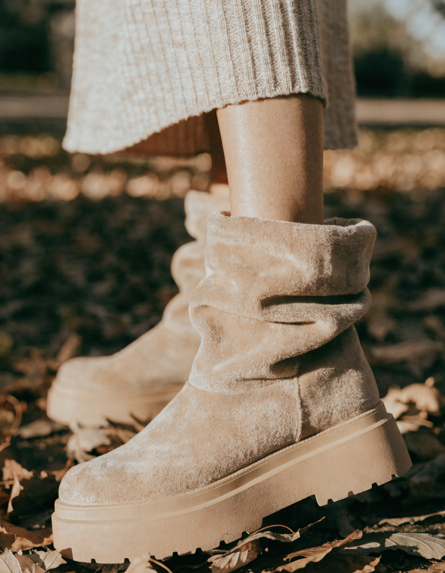 Beige fold-over cuff ankle boots with a chunky platform sole on autumn leaves