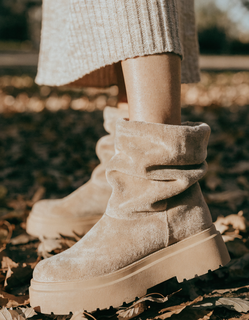Beige fold-over cuff ankle boots with a chunky platform sole on autumn leaves