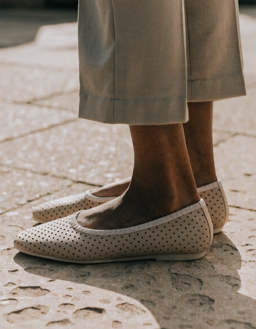 Beige perforated flats with whipstitch trim worn with cropped tailored trousers