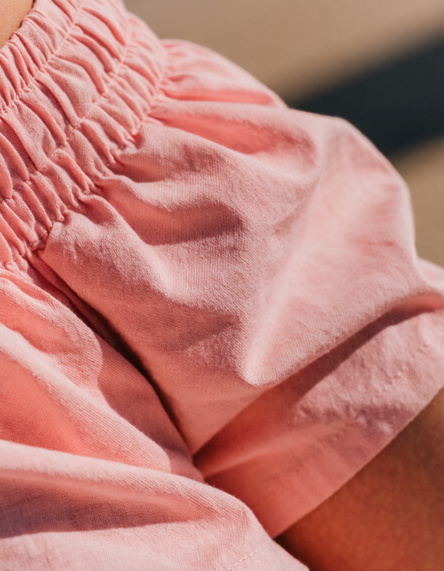 Detail of the pink woven shorts showing the elasticated waistband and loose leg