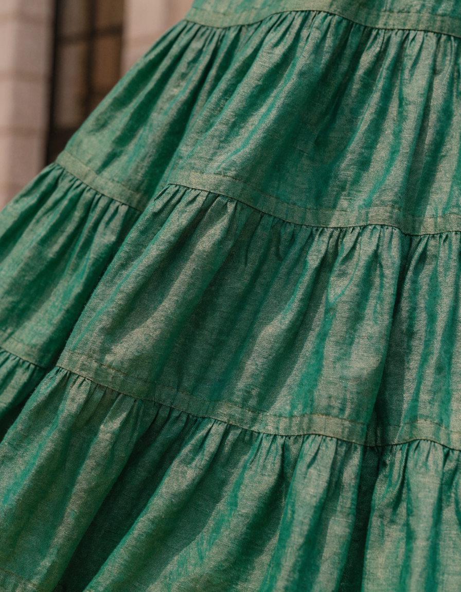 Detail of the layered tiers and seams of the green woven maxi skirt