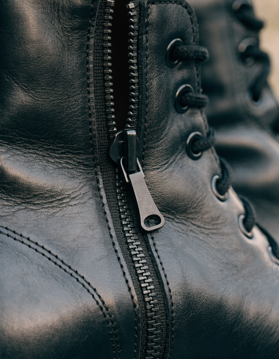 Detail of the side zip pull and lacing eyelets on a black ankle boot