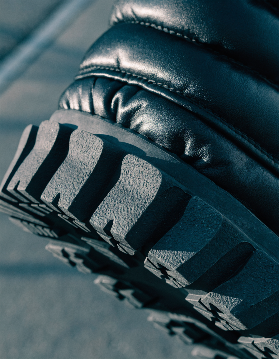 Detail of the deep lug outsole tread and padded collar of a black winter boot