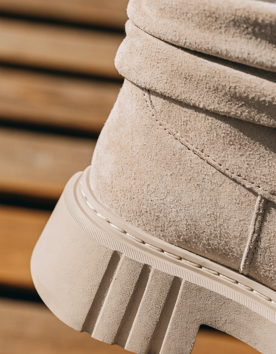 Detail of the chunky platform sole edge and folded cuff of a beige ankle boot