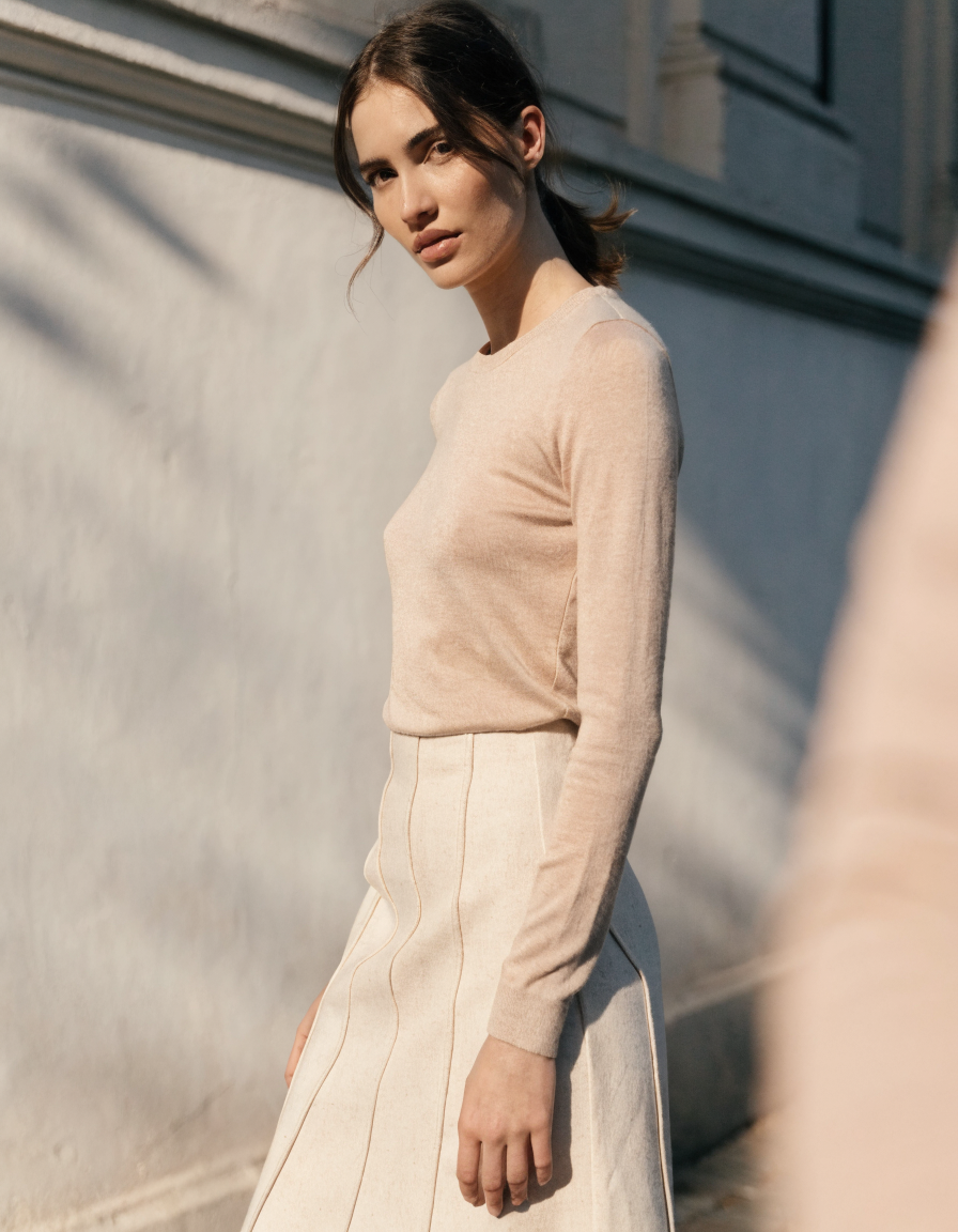 Three-quarter view of the cream panel seam midi skirt with a tucked-in fitted knit