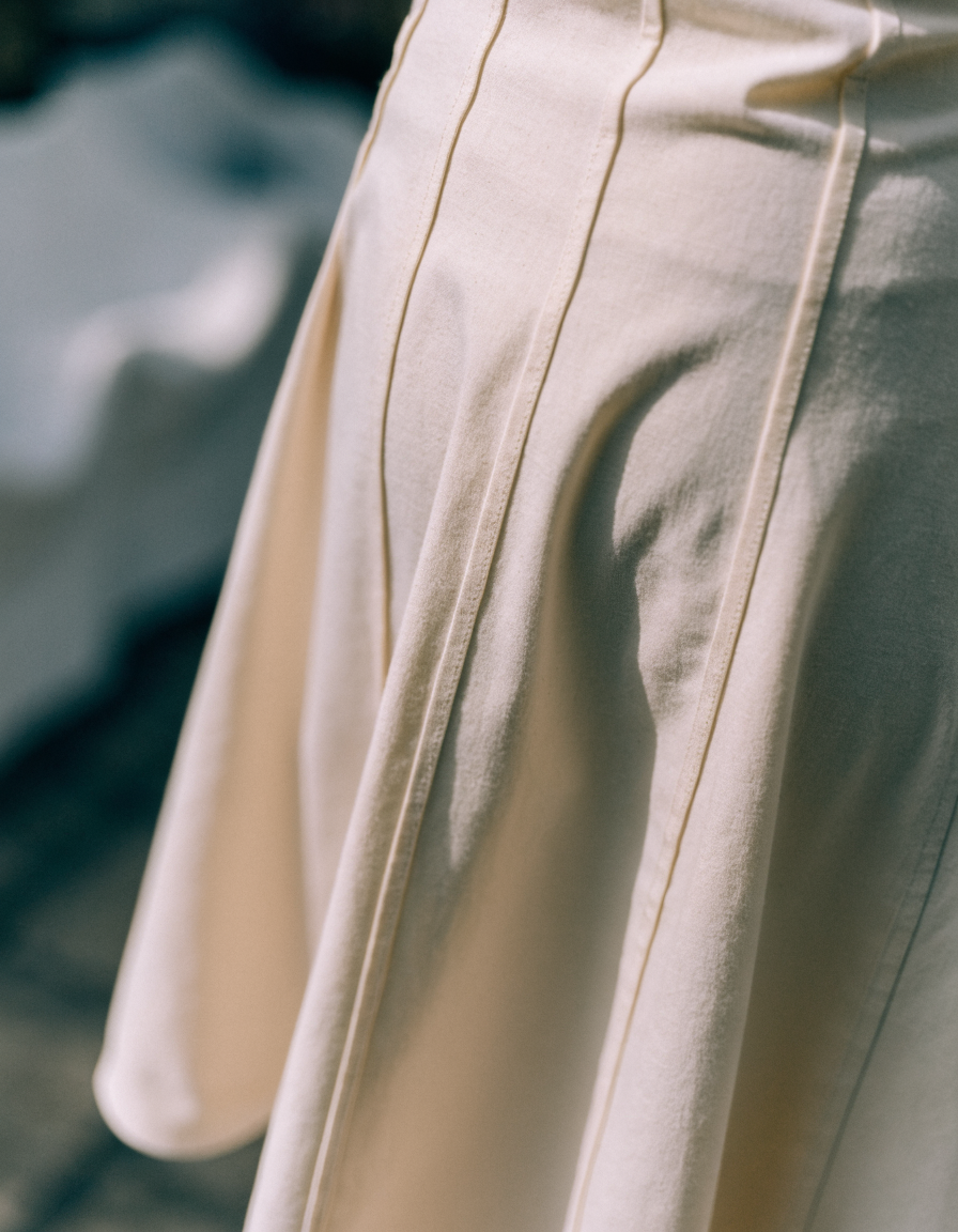 Detail of the vertical panel seams running down the cream midi skirt